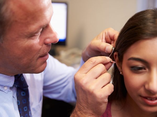 Doctor Fitting Female Patient With Hearing Aid
