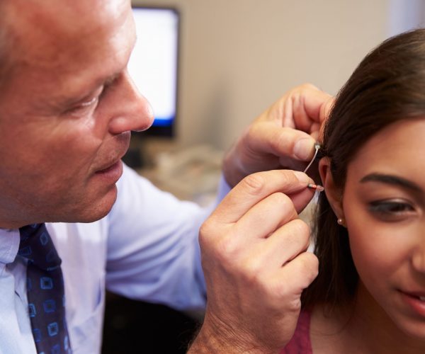 Doctor Fitting Female Patient With Hearing Aid